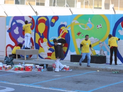 Alumnes de les escoles d'art i disseny pintant la tanca